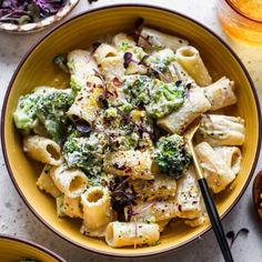 a bowl filled with pasta and broccoli on top of a table next to other bowls