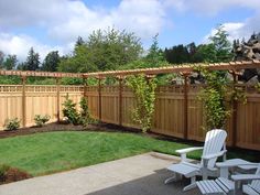 a backyard with a wooden fence and white lawn chairs