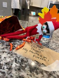 a red stuffed animal with a sign on it's head and some food in front of it