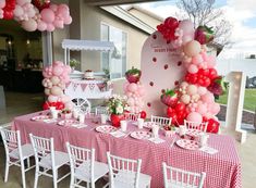 the table is set up for a party with pink, red and white balloons on it