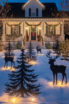 christmas decorations in front of a house with lights on the trees and reindeers outside