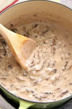 a wooden spoon in a pot filled with mushroom soup