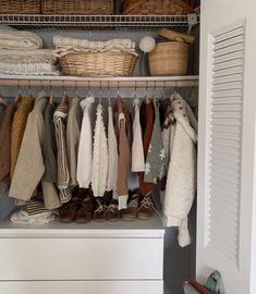 an organized closet with baskets and clothes hanging on the rails, including sweaters and shoes