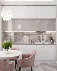 a white kitchen with marble counter tops and pink chairs around a round dining table in the center