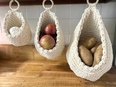 two bags with apples and potatoes hanging from hooks