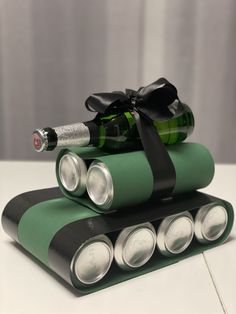 three green and black rolled up batteries with a bottle of wine in the middle on top