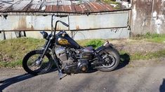 a black motorcycle parked on the side of a road next to an old rusted building