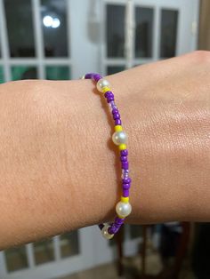 a woman's arm with a purple and yellow beaded bracelet