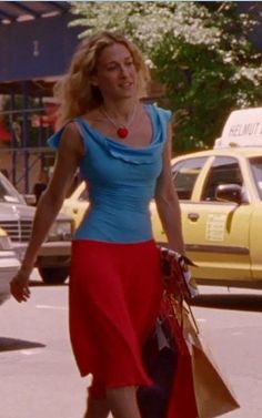 a woman is walking down the street with shopping bags in her hand and wearing a blue top