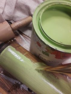 a green paint can sitting on top of a wooden table next to a rolling pin