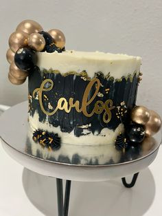 a black and white cake with gold balloons on it's top that says cakes