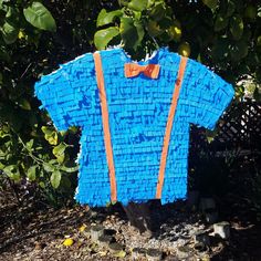 a blue shirt with orange suspenders and an orange bow tie hanging from a tree