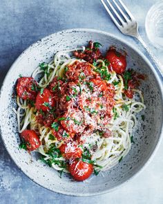 a white bowl filled with spaghetti and tomatoes