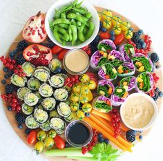 a platter filled with sushi, vegetables and dipping sauce