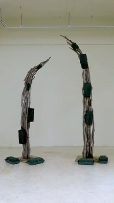 two sculptures made out of sticks and wood in an empty room with no one standing on the floor