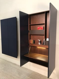 an open bookcase in the corner of a room next to two bookshelves