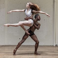 two people are doing acrobatic poses in front of a brick wall