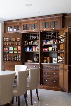 a dining room table and chairs in front of an open cabinet with spices on it