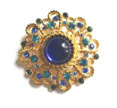 a blue and green brooch sitting on top of a white table