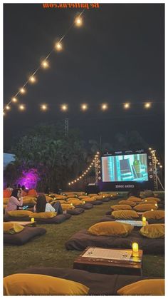 people are sitting on bean bags watching movies in the dark with lights strung over them