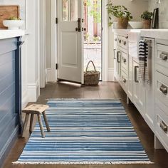 a blue and white striped rug in the middle of a kitchen with an open door