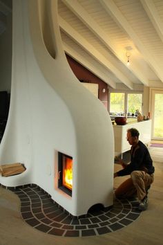 a man sitting in front of a fire place inside of a house on the floor