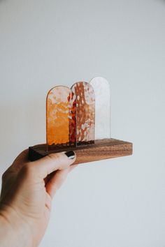 a hand is holding a piece of wood with two pieces of glass on it