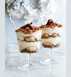 two desserts sitting on top of each other in wine glasses next to a christmas tree