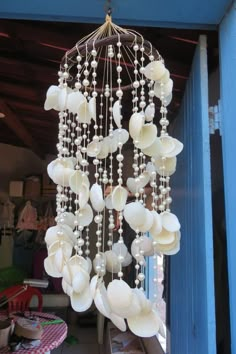 a wind chime hanging from the side of a blue building with lots of white shells