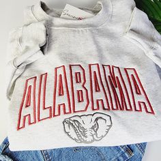 Experience the perfect blend of style and school spirit with our Alabama Elephant Crewneck Sweatshirt or Hoodie! Crafted in a classic ash grey hue, this shirt is designed to keep you cozy and comfortable, whether you're cheering in the stands or just showing off your roll tide pride around town. At the heart of its design is the iconic "Alabama" embroidery, boldly presented across the center chest. The word is intricately stitched in a vibrant crimson, capturing the essence of the University of Alabama's spirit. Complementing this is an elephant, rendered in grey, showcasing the school's beloved mascot with pride and precision. Made from high-quality materials, this shirt ensures both durability and a soft feel, making it ideal for daily wear. The crewneck design offers a relaxed fit, perf High School Spirit Wear, Alabama Elephant, Alabama Sweatshirt, School Spirit Wear, Clothes Embroidery Diy, Elephant Shirt, School Spirit Shirts, Crewneck Design, Spirit Shirts