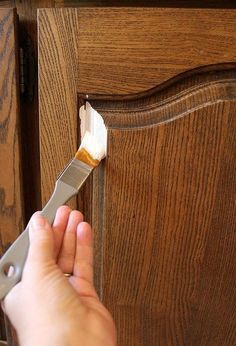 someone using a paint brush to apply wood grain on a cabinet door with an adhesive tape