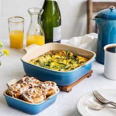 a blue casserole dish on a white table with other dishes and utensils