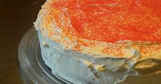 a cake with white frosting and orange sprinkles on it sitting on a plate