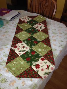 a quilted table runner sitting on top of a dining room table with a book