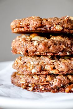 three cookies stacked on top of each other in a white plate with nuts and chocolate