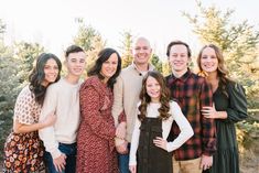 a group of people standing next to each other in front of some trees and bushes