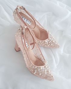 a pair of pink shoes with pearls on the toes and heels are sitting on a white sheet