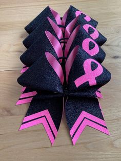 a pink and black ribbon with the word hope on it is laying on a wooden surface