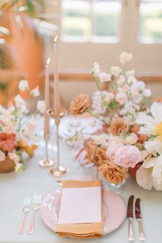 the table is set with pink and white flowers, silverware, and napkins