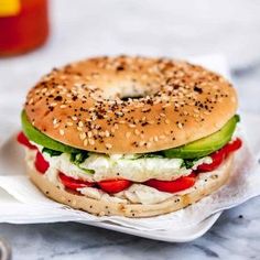 a bagel sandwich with cheese, lettuce and tomatoes