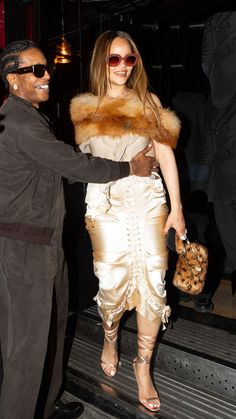 a woman in a white dress and fur stoler shaking hands with a man in a suit