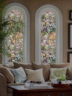 a living room filled with furniture and two large windows covered in stained glass window panes