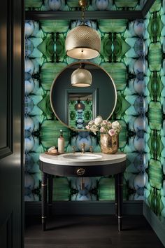 a bathroom with green and blue wallpaper and a round mirror on the side table