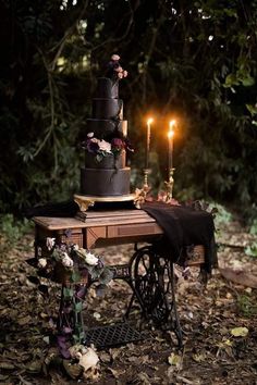 a table topped with a black cake and two candles