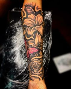 a woman's arm with flowers on it and a butterfly flying over the flower