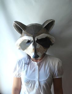 a woman wearing a raccoon mask standing in front of a white wall with her hands on her hips