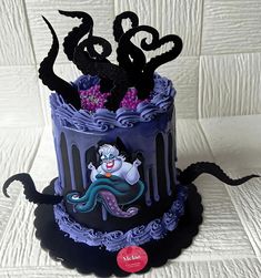 the cake is decorated with black icing and purple frosting, while an octopus sits on top