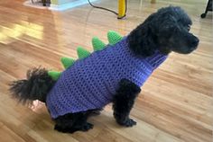 a black dog wearing a purple sweater with green spikes