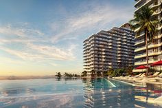 an outdoor swimming pool with lounge chairs and umbrellas in front of the hotel at sunset