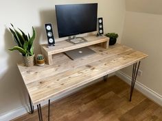 a wooden desk with a computer on top of it and speakers next to the monitor